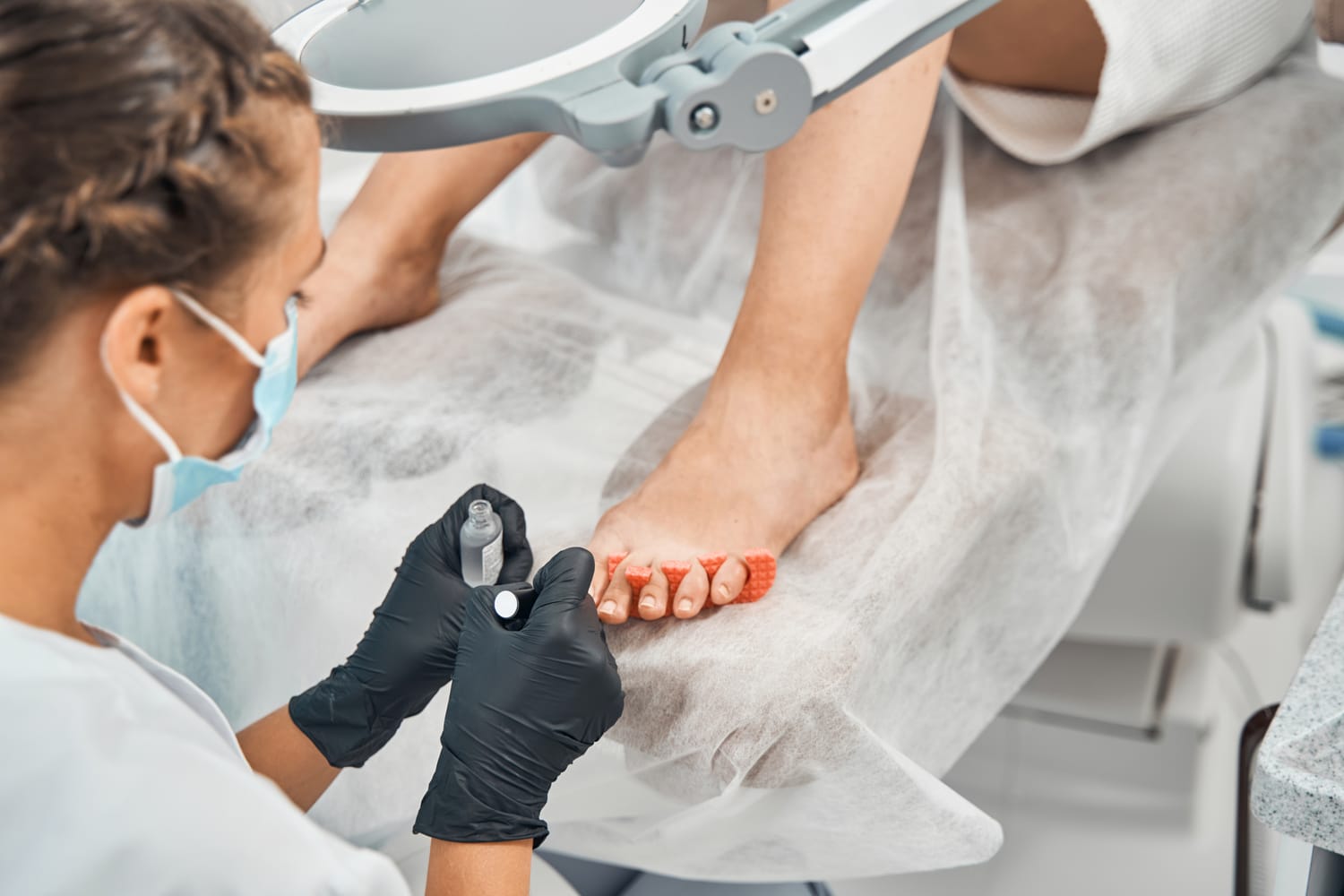 A Doctor wearing mask is treating toenails